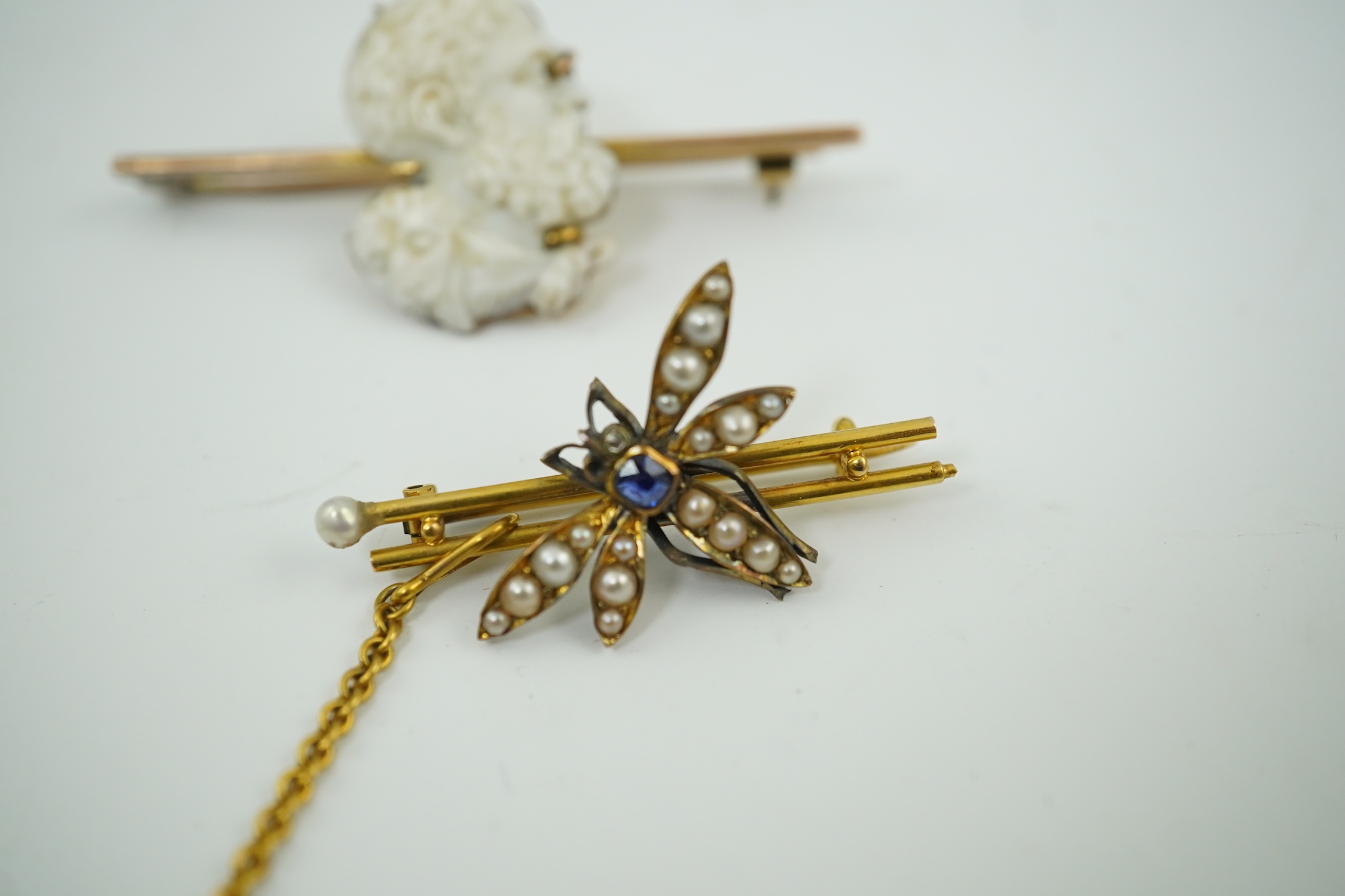 An Edwardian 15ct mounted cameo shell bar brooch, 49mm, together with a yellow metal, sapphire and split pearl cluster set dragonfly bar brooch, 11 grams. Condition - fair